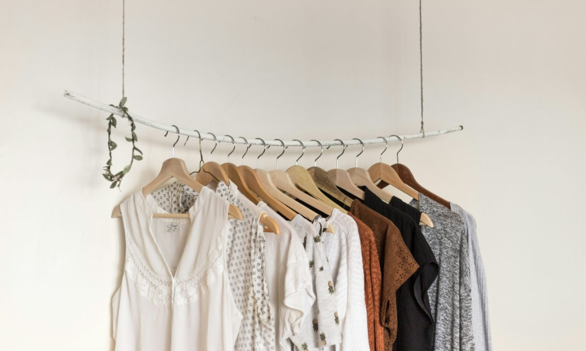 A simple hanging rail of clothes running from white summer blouses to brown and black autumn layers.