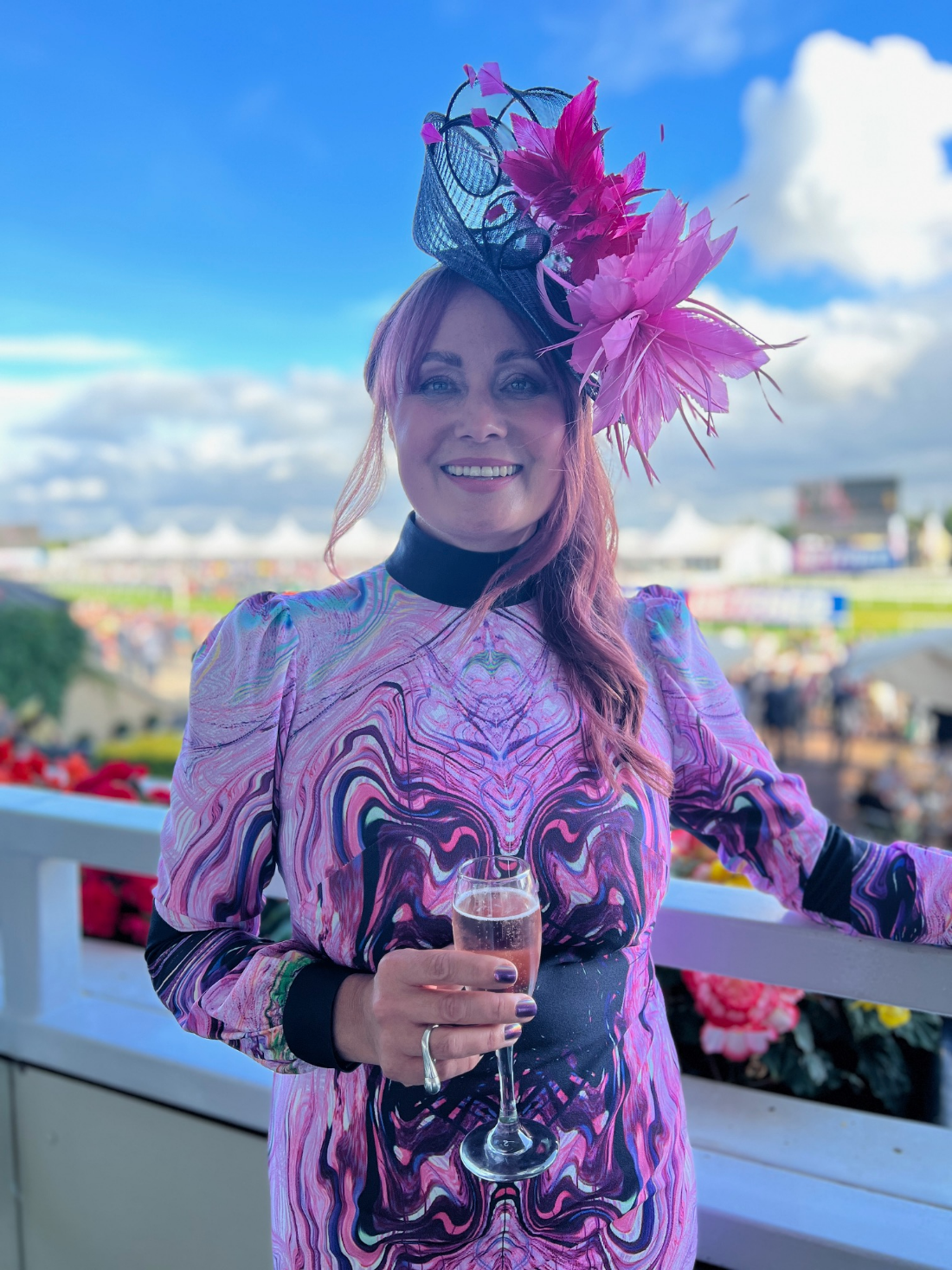 Estelle Pearce at the St Leger races in Doncaster, wearing a pink marbled dress she designed and a matching feathered fascinator