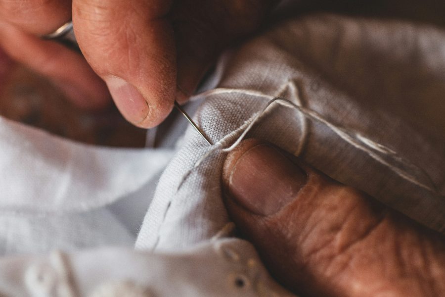Hands stitching a repair into linen by hand