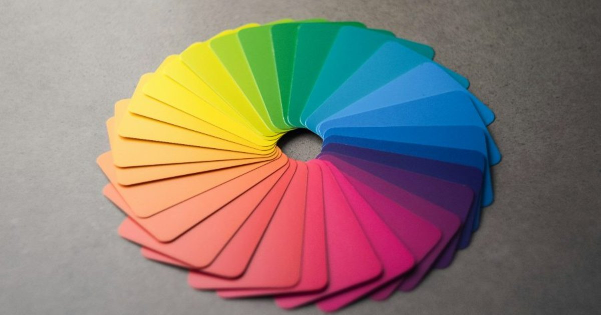 A fan of colour swatches opened in a full spectrum circle on a grey surface.